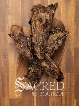 3 beef bones which are the sternum (breast plate) from cows are in a wooden bowl on a wooden table top. Lots of meat to eat.