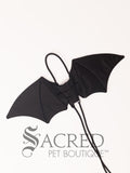 The Small size black bat costume wings sit on a white background. A loop at the top goes over the dogs head allowing the wings to sit over the dogs shoulders or wherever you think it looks best. The tails of the loop allow the head loop to be pulled longer or shorter and can then be tied under the dogs belly, or around its harness.