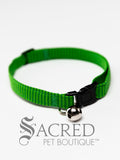 A cat collar is shown against a plain white background. The pattern of the fabric is mid green, with darker green regularly spaced stripes. The collar has a black plastic breakaway buckle and adjuster, and a silver bell on a silver split ring.