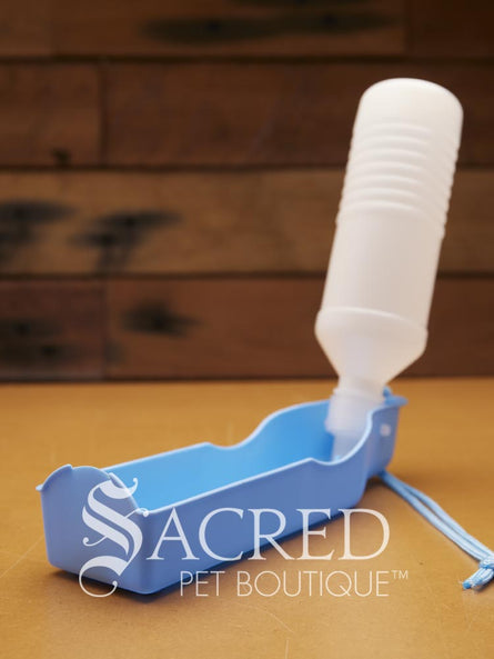 Pet water bowl with bottle attachment on a wooden surface, branded 'Sacred Pet Boutique'.