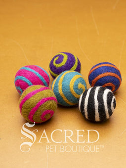 A pile of colourful wool felt balls with polka dots sits on a wooden table. Suitable for all cats and small to teacup sized dogs.
