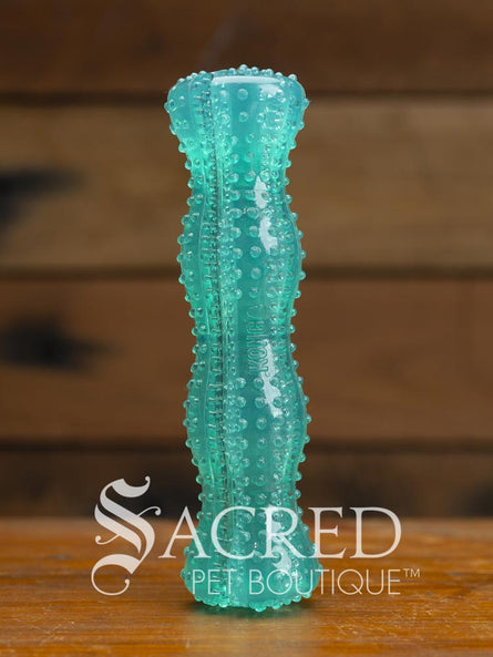 Teal textured dental dog toy with treat crevices and stimulation nubs on a wooden surface with 'Sacred Pet Boutique' branding.