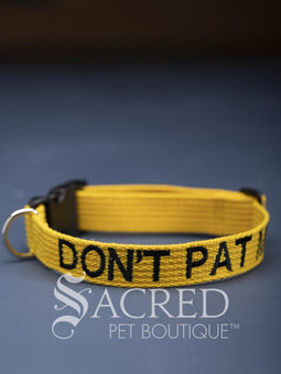 A group of dog collars and leashes with embroidered safety messages in white or black. On a grey background with a Sacred Peet Boutique watermark.