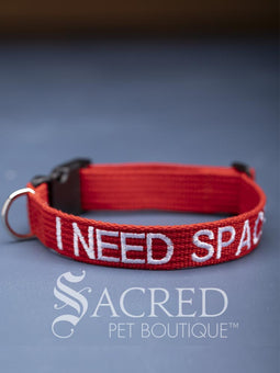 A group of dog collars and leashes with embroidered safety messages in white or black. On a grey background with a Sacred Peet Boutique watermark.