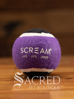 A single blue and orange tennis ball sits on a wooden table with a wooden background. The ball is solid foam, so it won't pop, has dog friendly fuzz and does not squeak.