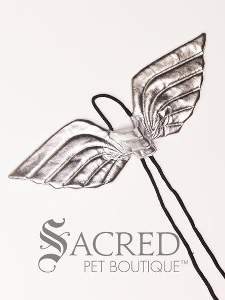 The small size silver angel costume wings sit on a white background. A loop at the top goes over the dogs head allowing the wings to sit over the dogs shoulders or wherever you think it looks best. The tails of the loop allow the head loop to be pulled longer or shorter and can then be tied under the dogs belly, or around its harness.