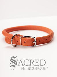 A black, round, soft leather dog collar with a metal buckle clasp. Our beautiful Soft Round (Rolled) leather collars are highly recommended for long haired dogs. Round or rolled collars reduce the amount of matting, tangling and flattening of the dogs fur. All collars are hand made and stitched with wax thread, from the finest quality soft leather wrapped and stitched around a nylon inner cord for added strength.Image on a white background, with the Sacred Pet Boutique logo.