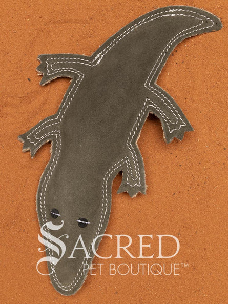 Steve the Crocodile is a green Buffalo suede dog toy with multiple rows of stitching, on a wooden background. A white Sacred Pet Boutique watermark.