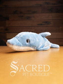 A bright red squid sits on a wooden table. It has embroidered eyes and short tentacles.