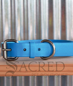A dog wearing a pink Coopers collar with a white background and a grey Sacred Pet boutique watermark.