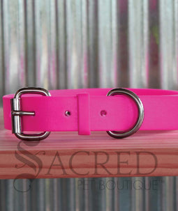 A dog wearing a pink Coopers collar with a white background and a grey Sacred Pet boutique watermark.