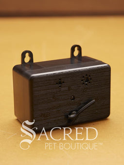 A black bark box sits on a wooden surface with a white Sacred Pet Boutique logo.