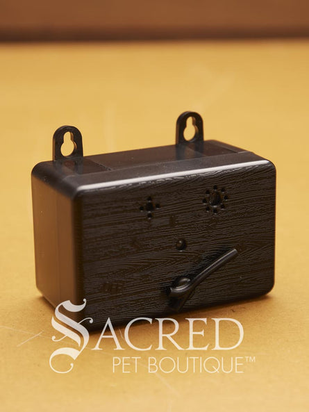 A black bark box sits on a wooden surface with a white Sacred Pet Boutique logo.