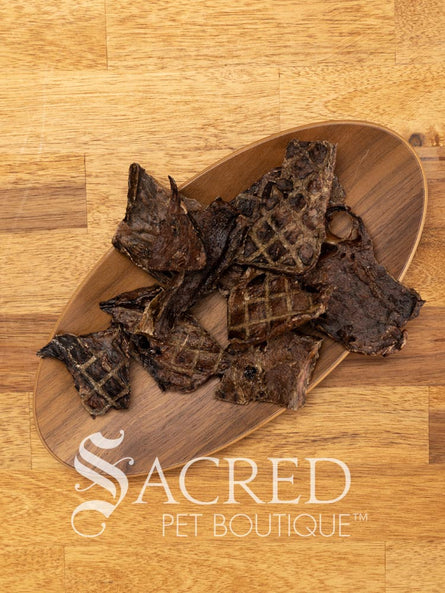 A small wooden plate on a wooden table holds 10 pieces of thinly sliced beef lung crisp, a perfect treat for training dogs. The treats are easy to break into smaller pieces.