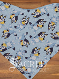 A Bluey character dog patterned bandana spread flat on wooden table and with a white Sacred Pet Boutique watermark