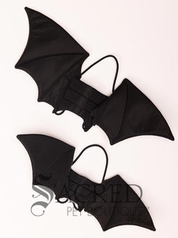 The Small size black bat costume wings sit on a white background. A loop at the top goes over the dogs head allowing the wings to sit over the dogs shoulders or wherever you think it looks best. The tails of the loop allow the head loop to be pulled longer or shorter and can then be tied under the dogs belly, or around its harness. 