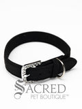 A black faux suede dog collar with sparkling rhinestone accents and a rhinestone-encrusted buckle on white background and Sacred Pet Boutique watermark.