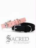 A pink and black faux suede dog collars with sparkling rhinestone accents and a rhinestone-encrusted buckle on white background and Sacred Pet Boutique watermark.