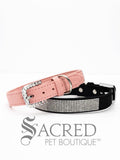 A pink and black faux suede dog collars with sparkling rhinestone accents and a rhinestone-encrusted buckle on white background and Sacred Pet Boutique watermark.