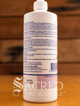A bottle of Epi-Otic SIS ear cleanser for pets, with branding and instructions printed on the label, placed on a wooden surface. Features Sacred Pet Boutique watermark.