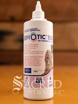 A bottle of Epi-Otic SIS ear cleanser for pets, with branding and instructions printed on the label, placed on a wooden surface. Features Sacred Pet Boutique watermark.