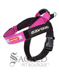 A pink Express Harness is shown against a white background with a dark grey watermark. The front chest strap and the girth straps are adjustable. There is a control handle and sliding leash attachment point. The velcro name tag is the standard Ezydog name tag that comes with every Express harness
