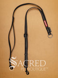 A black EzyDog Soft Webbing Coupler, designed for walking two small dogs, with adjustable nylon webbing and a brand label attached. On a wood background with a white Sacred Pet Boutique watermark.