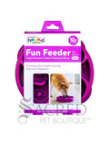 Outward Hound Fun Feeder mini dog toy in purple, shown in its retail packaging box. The box features the Hound brand logo and a picture of a dog eating from the toy. There is a white background and a grey Sacred Pet Boutique watermark.