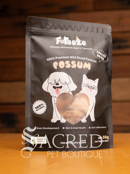 A packet of Freeze dried Tasmanian possum meat sits on a wooden table with a wood plank background. A clear window in the pack shows the pieces to be approximately 2 to 4 cm pieces.