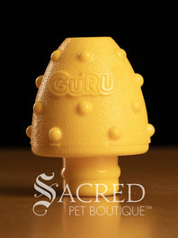 Blue, teal and yellow textured pet enrichment treat toys with 'Guru' branding on a dark background, featuring the 'Sacred Pet Boutique' logo.