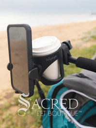 The Ibiyaya cup and phone holder is attached to a blue Happy Pet Stroller. and is being walked along a beach front. Hmm, coffee!