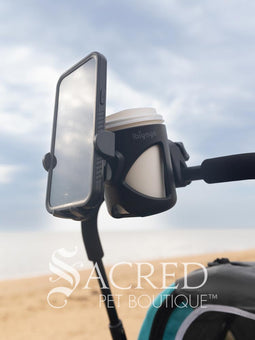 The Ibiyaya cup and phone holder is attached to a blue Happy Pet Stroller. and is being walked along a beach front. Hmm, coffee!