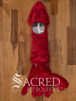 A bright red squid sits on a wooden table. It has embroidered eyes and short tentacles.