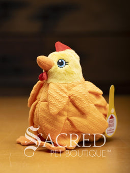 A bright yellow chicken with overlapping fabric feathers, flappy feet and embroidered eyes sits on a wooden surface. A white Sacred Pet Boutique watermark.