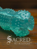 Turquoise dog toy with textured surface showing crevices for treats and nubs for interest on a wooden background, branded as Sacred Pet Boutique