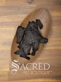Pieces of air dried lamb liver in a wooden bowl sitting on a wooden table top. A white Sacred Pet Boutique watermark.