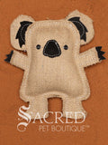 Kevin the Koala is a jute dog toy with wool felt detail and multiple rows of stitching, on a wooden background. A white Sacred Pet Boutique watermark.