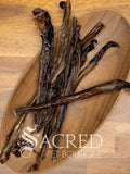 several dried pork chews in a wooden plate on a wooden background. With a white Sacred Pet Boutique watermark.