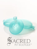 Three translucent aqua squeakers arranged on a white reflective surface with the Sacred Pet Boutique logo printed at the bottom.
