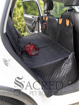 Rossi, the Italian Greyhound, sits in the back seat of an SUV. The Rigid Base Car Seat hammock protects the seats and doors, without letting him fall into the foot well. Mesh pockets provide storage. A mesh barrier between the front seats allows vision both ways. Easy to clean comfortable water proof fabric is durable. Holes for a car seat belt attachment keep him safe and restrained.