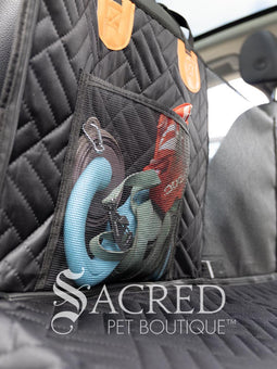 Rossi, the Italian Greyhound, sits in the back seat of an SUV. The Rigid Base Car Seat hammock protects the seats and doors, without letting him fall into the foot well. Mesh pockets provide storage. A mesh barrier between the front seats allows vision both ways. Easy to clean comfortable water proof fabric is durable. Holes for a car seat belt attachment keep him safe and restrained.