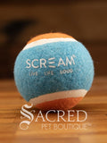 A single blue and orange tennis ball sits on a wooden table with a wooden background. The ball is solid foam, so it won't pop, has dog friendly fuzz and does not squeak.