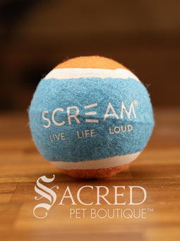 A single blue and orange tennis ball sits on a wooden table with a wooden background. The ball is solid foam, so it won't pop, has dog friendly fuzz and does not squeak.