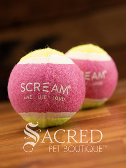 A single blue and orange tennis ball sits on a wooden table with a wooden background. The ball is solid foam, so it won't pop, has dog friendly fuzz and does not squeak.