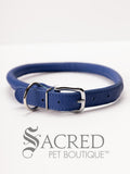A blue, round, soft leather dog collar with a metal buckle clasp. Our beautiful Soft Round (Rolled) leather collars are highly recommended for long haired dogs. Round or rolled collars reduce the amount of matting, tangling and flattening of the dogs fur. All collars are hand made and stitched with wax thread, from the finest quality soft leather wrapped and stitched around a nylon inner cord for added strength.Image on a white background, with the Sacred Pet Boutique watermark.