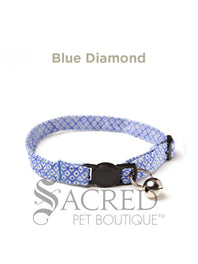 A cat collar is shown against a plain white background. The pattern of the fabric is pink with white polker dots. The collar has a black plastic breakaway buckle and adjuster, and a silver bell on a silver split ring.