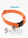 An tangarine and orange striped soft fabric cat collar with black plastic hardware and a silver bell with a safety breakaway buckle on a white background. A Sacred Pet Boutique watermark