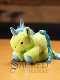 Lime green plush unicorn cat toy with blue and silver glitter dots on the hooves, horn and inside the ears. A soft blue mane and curly ribbons of blue and green for a tail. Sitting on a wooden background and has a grey Sacred Pet Boutique watermark. 