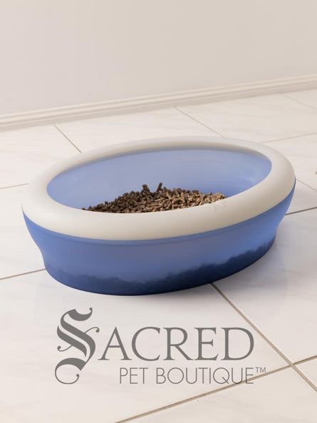 A blue Vicci litter tray in a white room on a white tiled floor. It is filled with kitty litter.