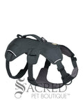 A grey dog harness with adjustable straps and a top handle, plus three leash attachment points, shown against a plain white background with a 'Sacred Pet Boutique' watermark at the bottom.